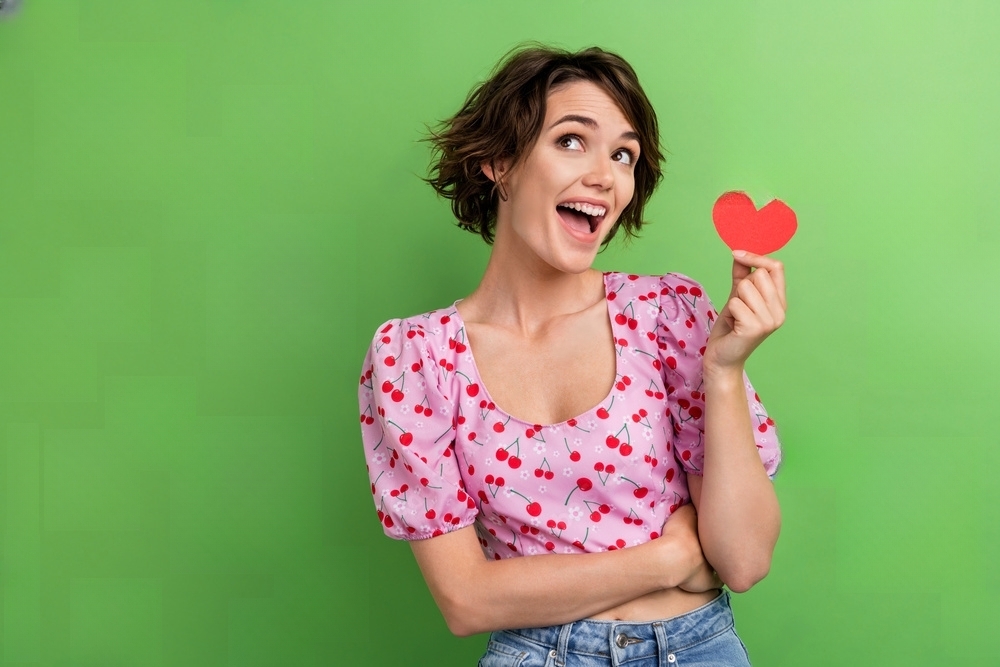 Mulher com um coração na mão e uma blusa de estampa de cerejas